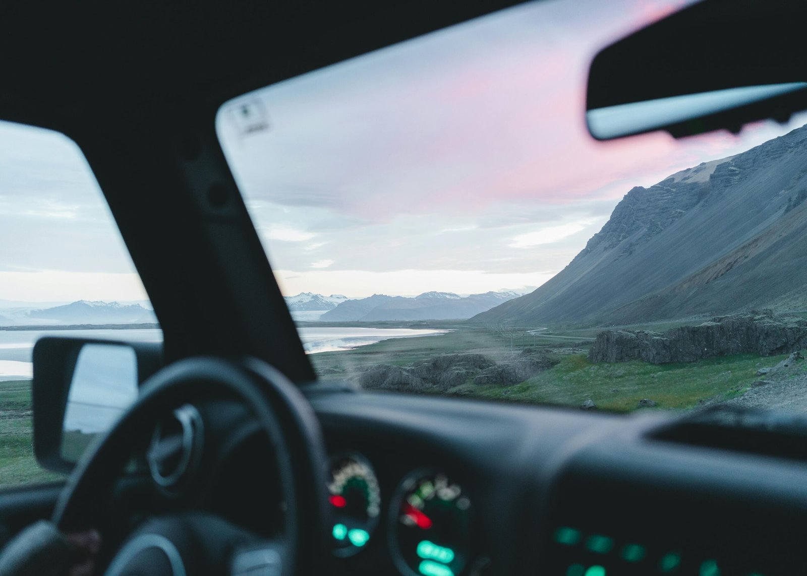 View through car window of Iceland's stunning mountains and rivers during a scenic drive at sunset.